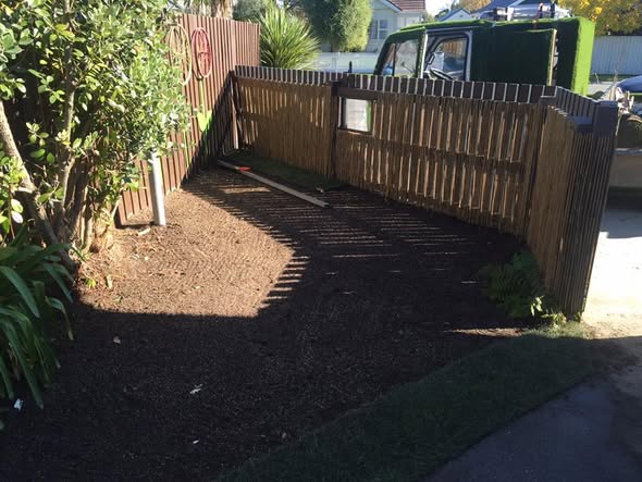 The Smileys Property Rescue work ute on a residential street beside a freshly bark-mulched garden bed and paling fence